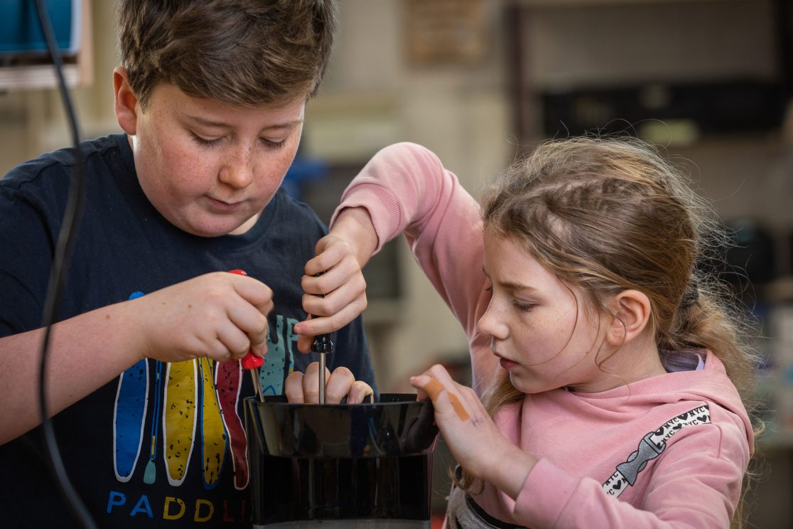 Mädchen und Junge schreiben an alter Kaffeemaschine herum